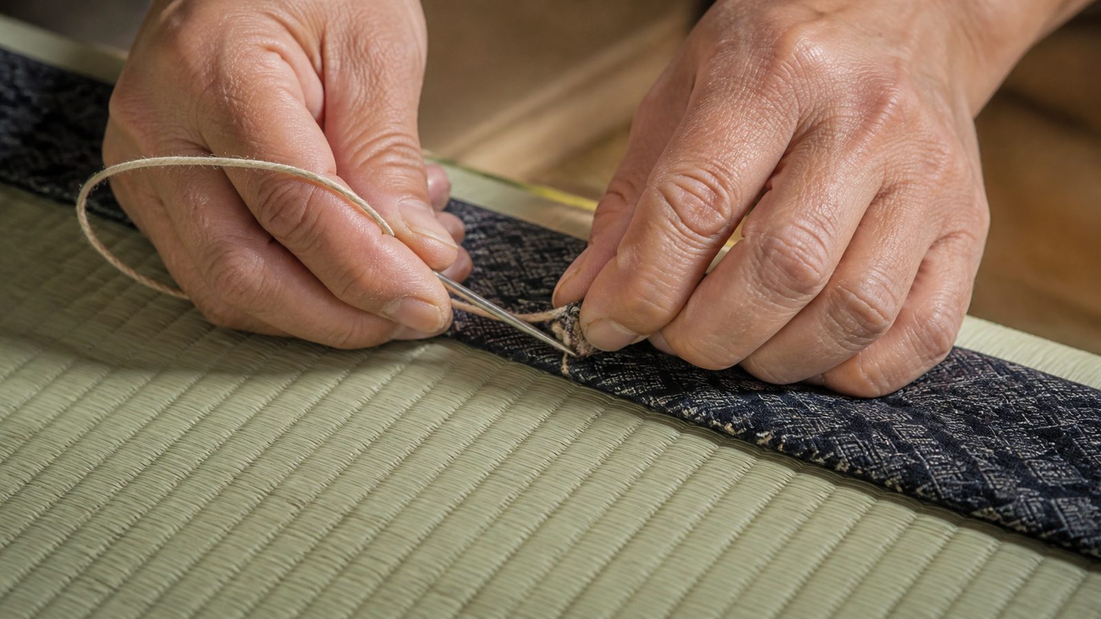 畳縁を畳針で縫う、職人の手元